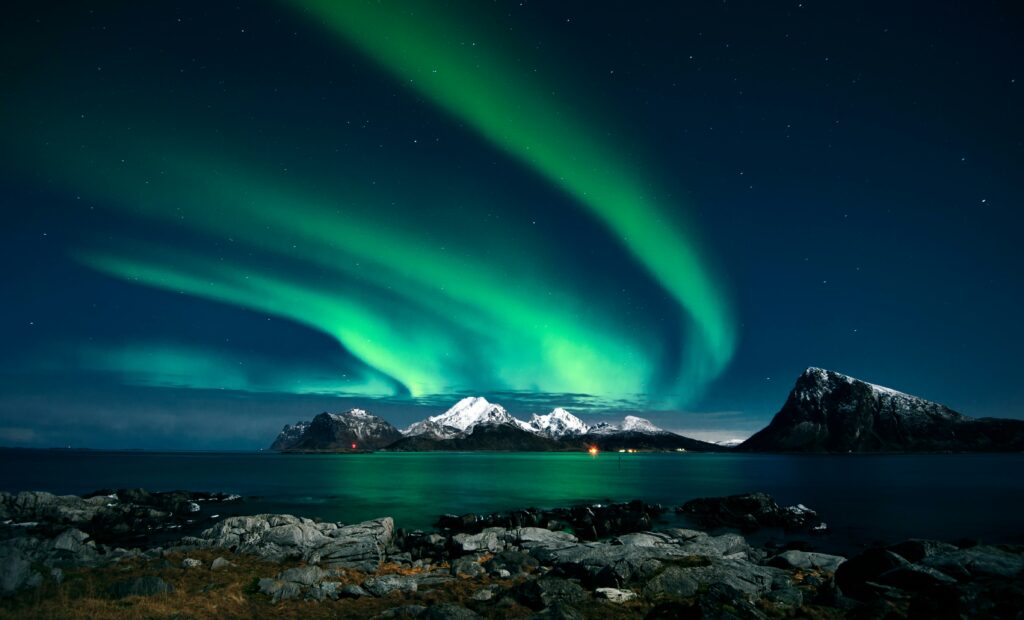 pexels-photo-1933319-1933319 Breathtaking northern lights display over snow-covered mountains and serene waters in Lofoten, Norway.